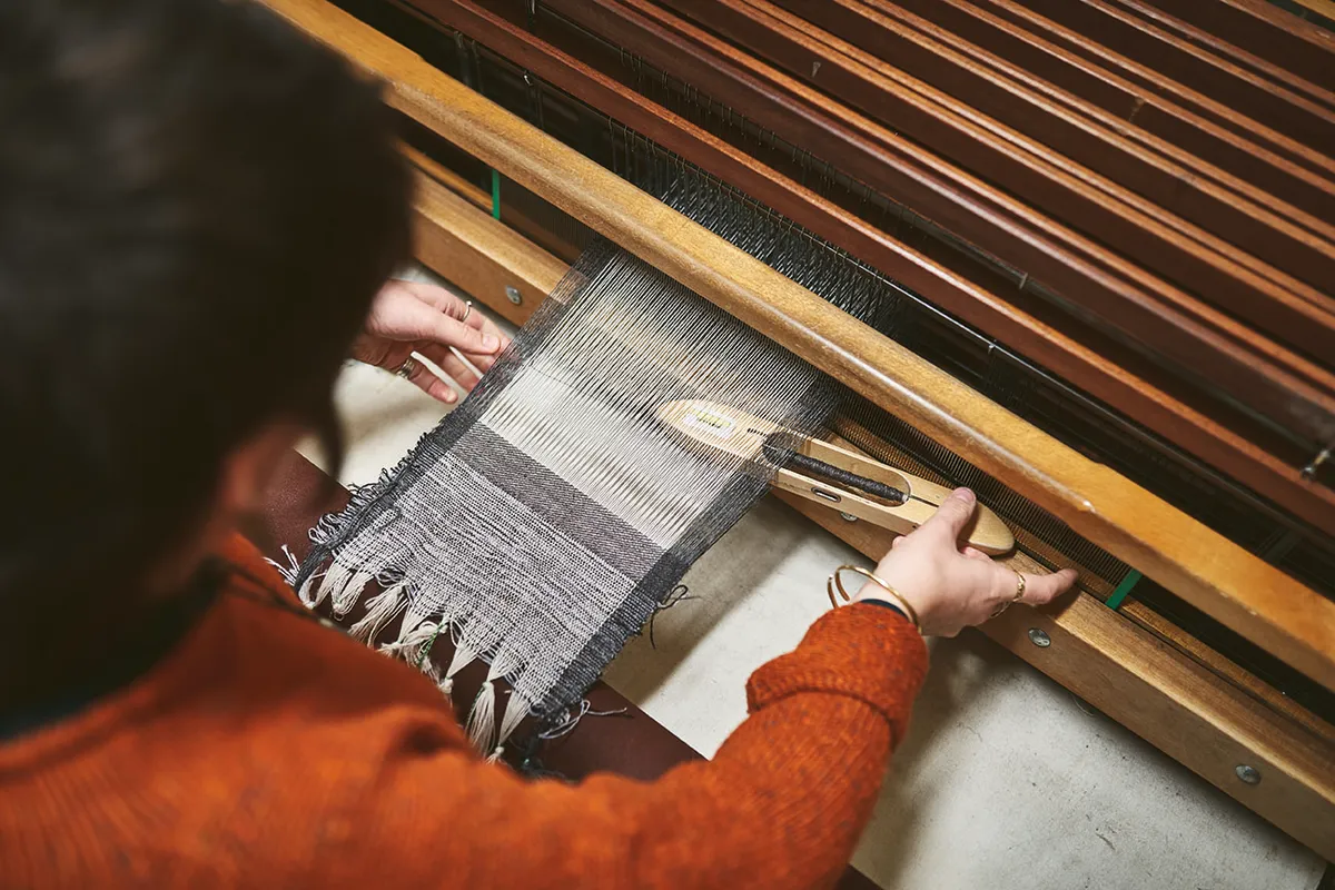 A member of the mill working on the hand loom