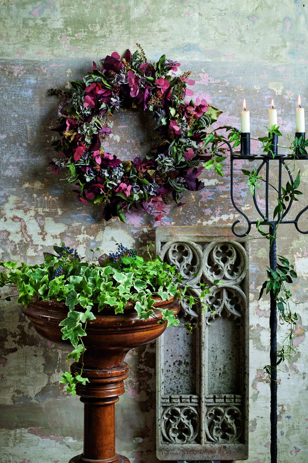 An alter and piece of stonework with a dried flower wreath and swathes of ivy.