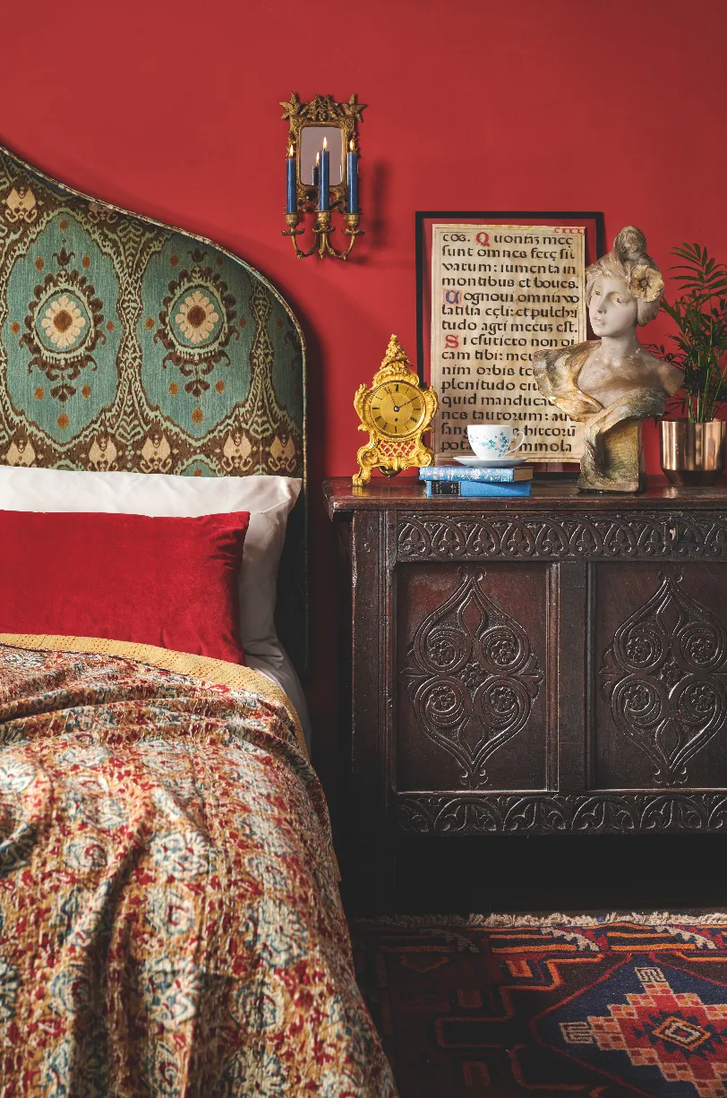 Antique oak coffer, Iznik rug and brass sconce create a Moroccan feel in this bedroom scene.