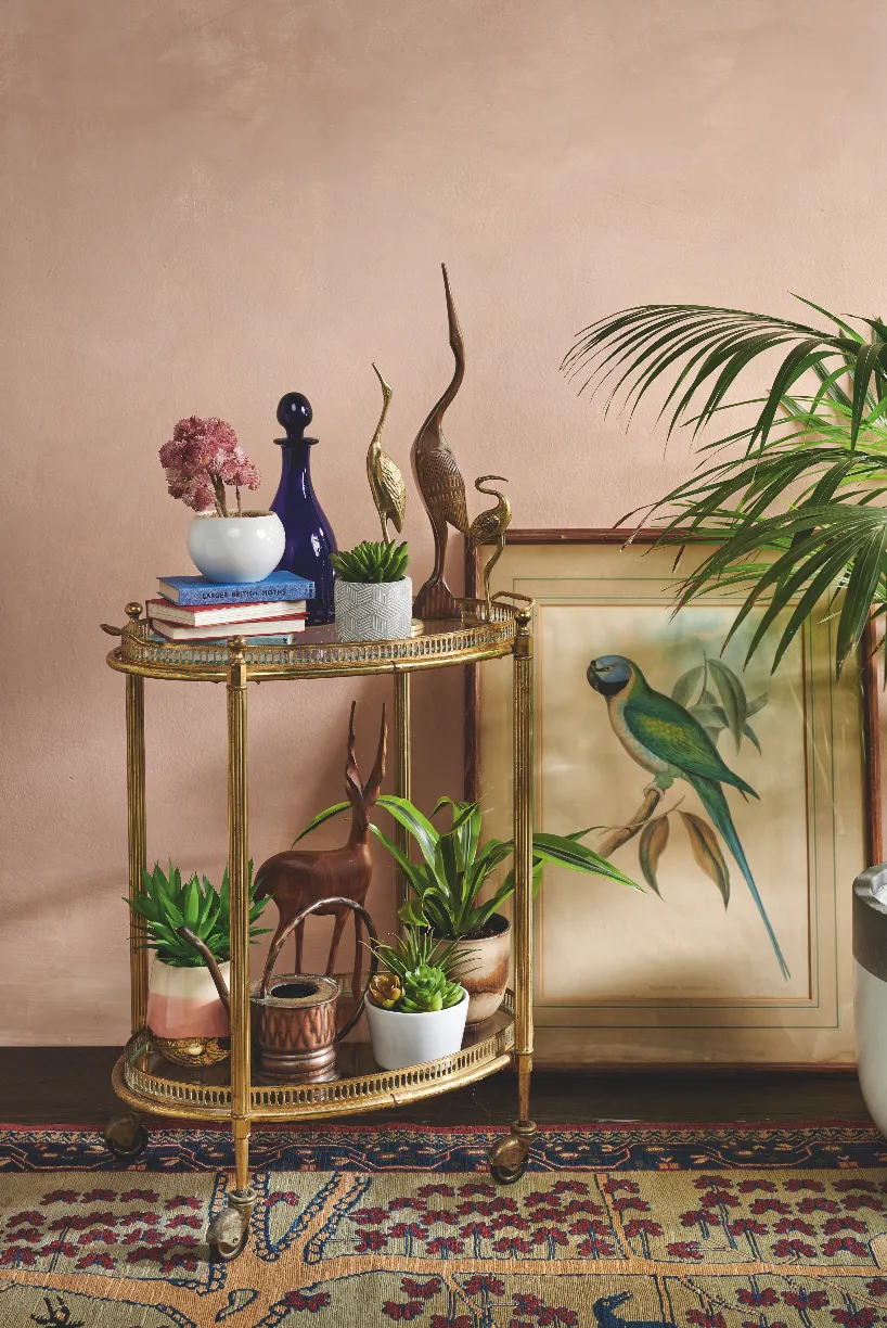 An antique drinks trolley stacked with mid-century birds and potted houseplants.