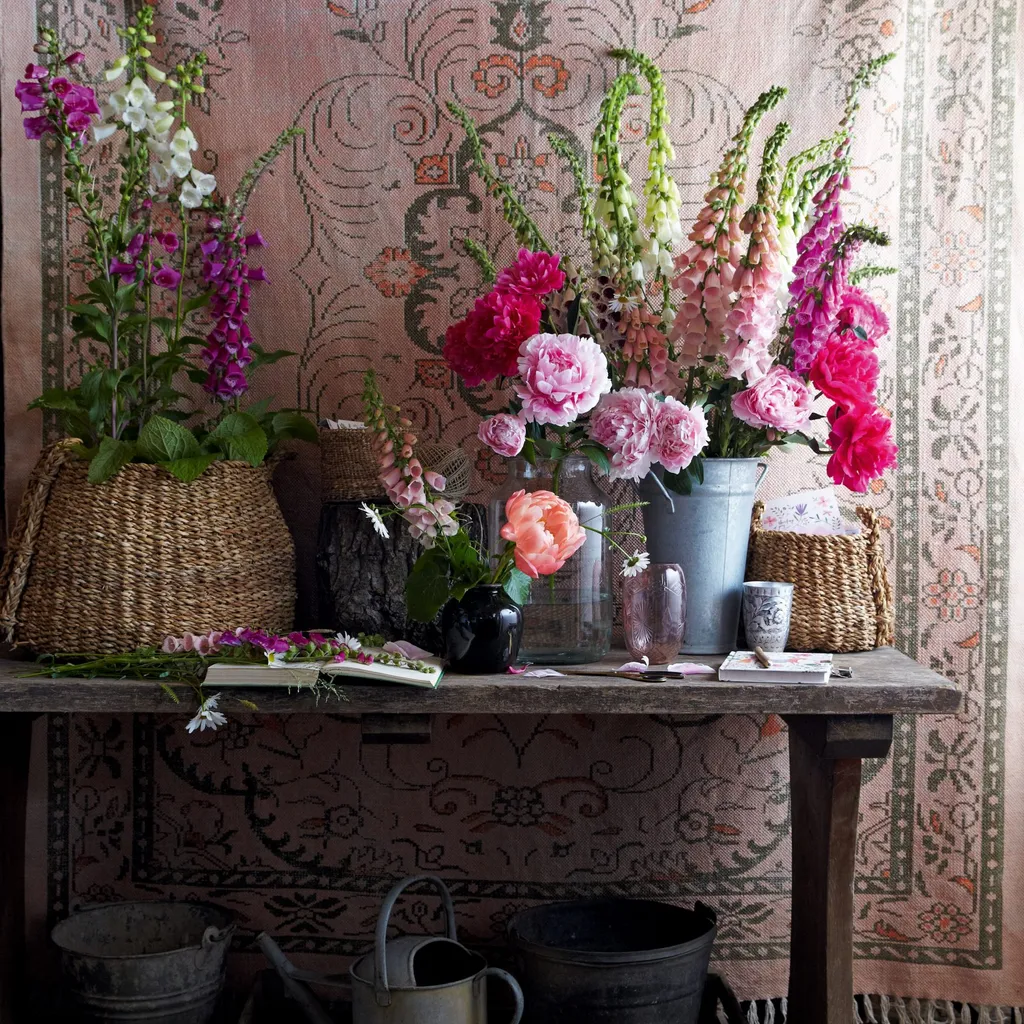 Antique rug used as a backdrop to a display of flowers on a wooden table