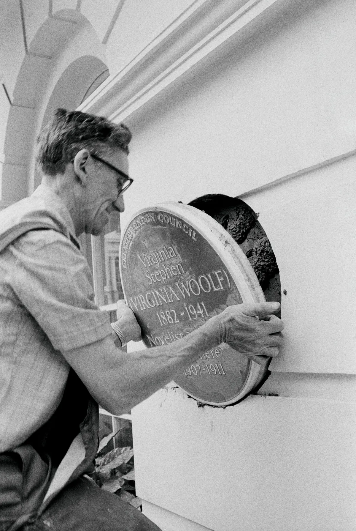 Frank Barnes places the Virginia Woolf Blue Plaque on a London building