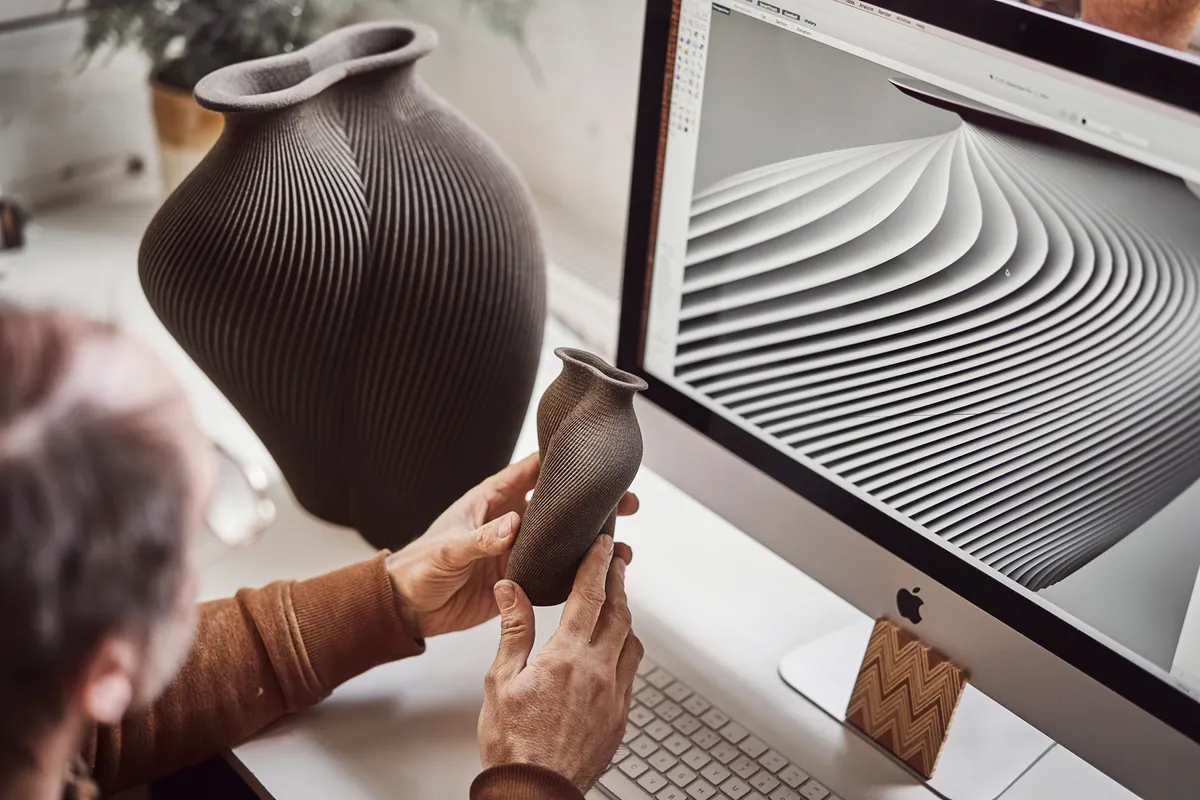 Gareth studies a model of his 3D-printed sand vessel alongside the initial drawings