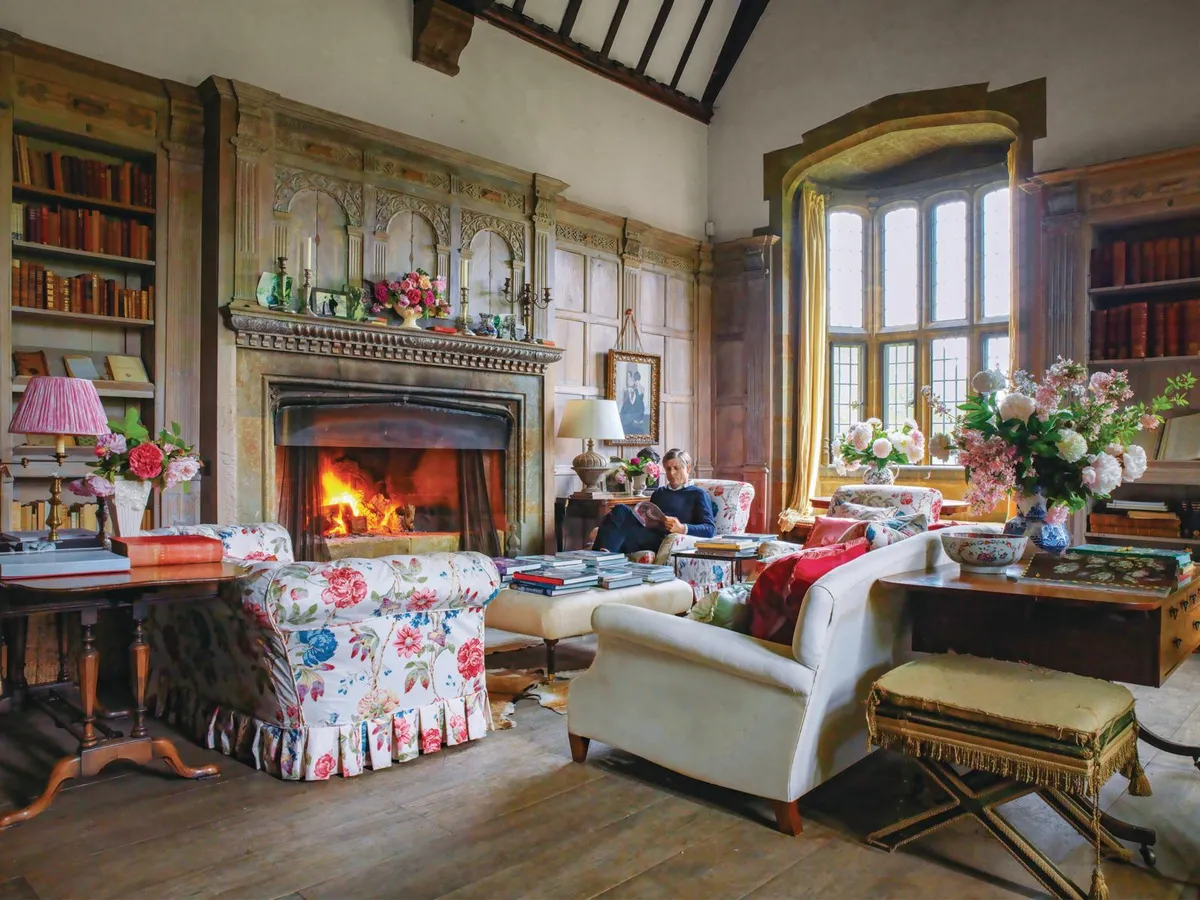Wardington Manor: library with roaring fire and faded-chintz sofa.