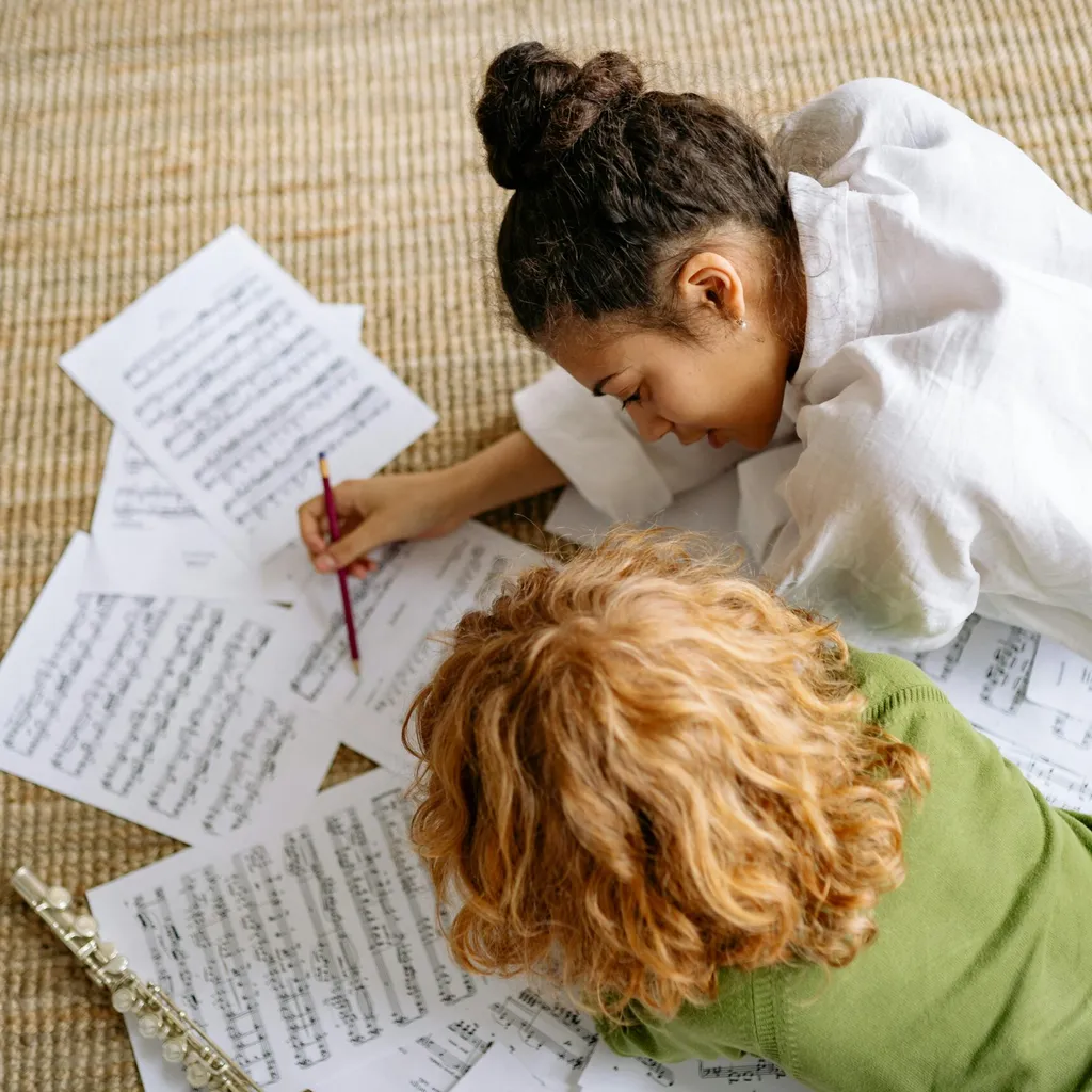 Children looking at sheets of music together on the floor