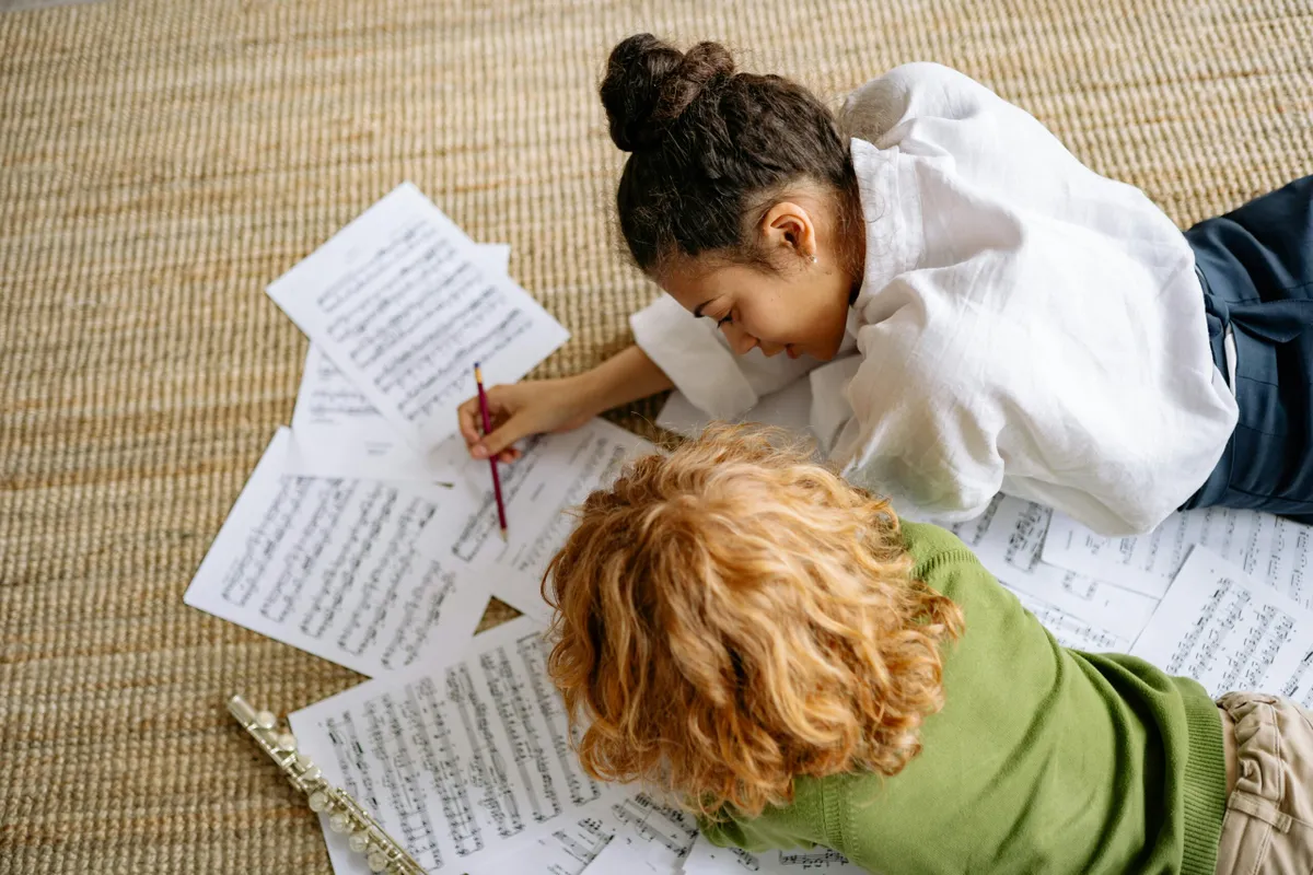 Children looking at sheets of music together on the floor