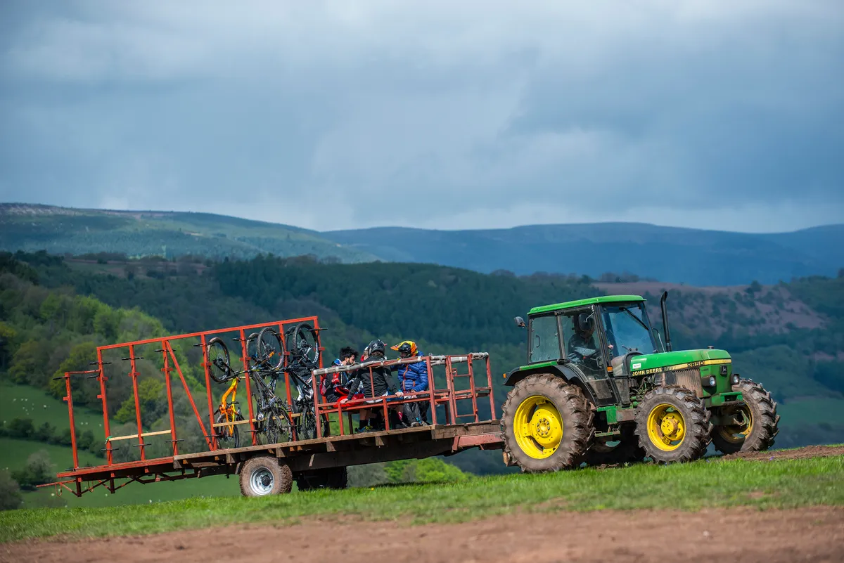 Riders sitting in the back of an uplift trailer being towed up by a tractor