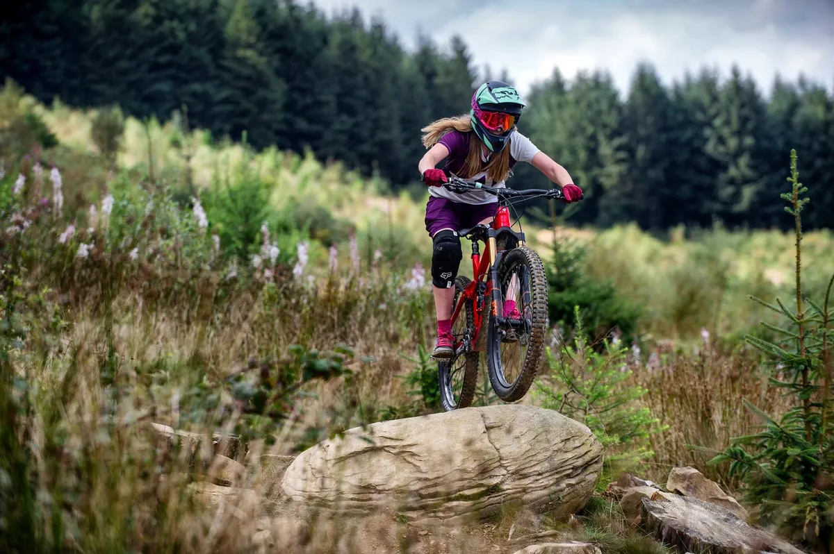 female rider jumps over rock at bikepark wales