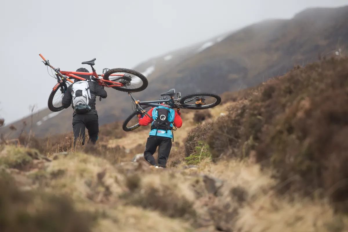 Neil Stewart and Brett Penfold carry their bikes up a steep climb on the Great Glen Way