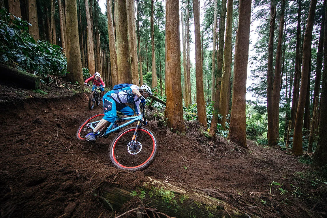Two riders cornering in the forests of the Azores