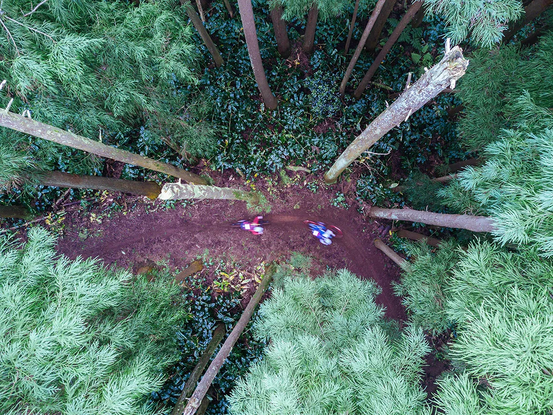 Shot from the treetops looking down on two riders on a snaking trail