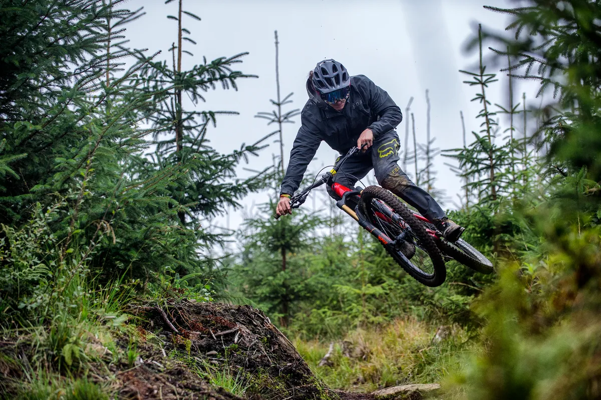 Mike Beasley jumps off a tree stump at BikePark Wales