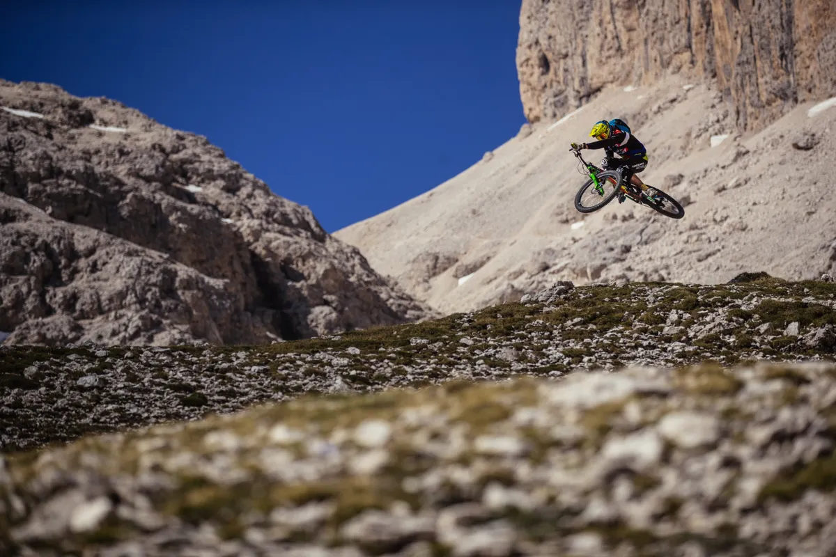 Cédric Gracia doing a bike jump in the Italian Dolomites