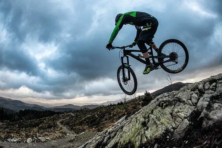 Downhill rider Adam Brayton jumping off rocks at Coed-y-Brenin in north Wales