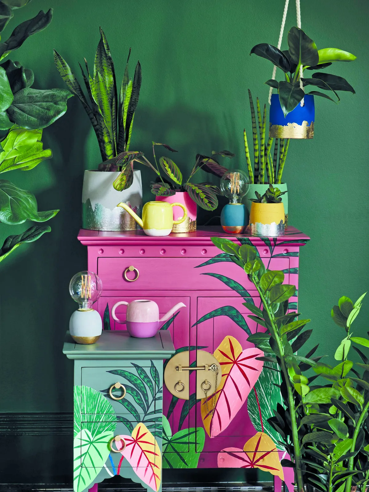 If you don’t have the space for plants, botanical motifs will boost the jungle feel Pink Iro cabinet, £565; green Iro bedside table, £198; Tierra foiled base plant pot, collection from £8.50; mini ceramic watering cans, £19.50 each, all Oliver Bonas