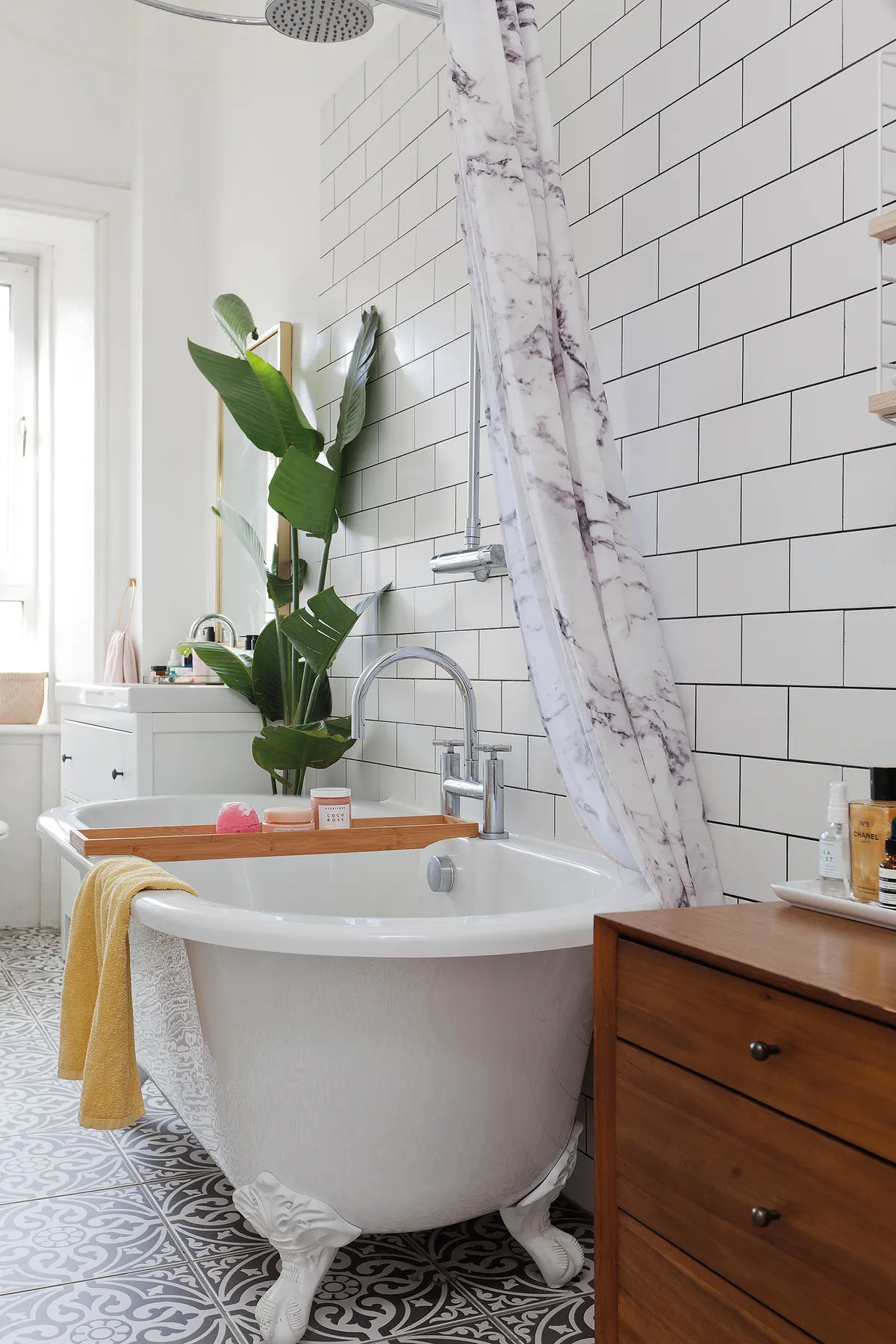 Plenty of plants and fresh white tiles create a serene look in the bathroom. Wanting to steer away from built-in furniture, Kate has used baskets for storage, as well as a vintage-look dresser and chest of drawers