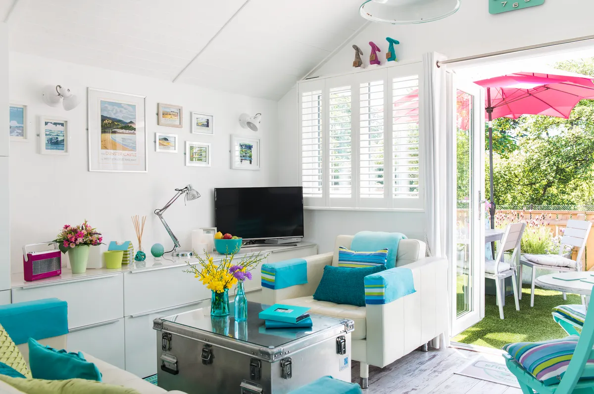 Real home - inside of beach hut with white shutters and turquoise accessories