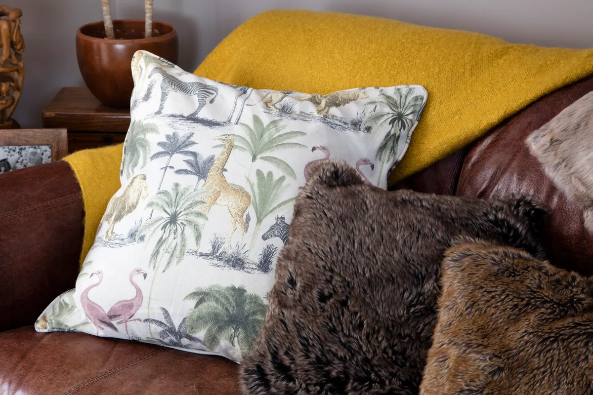 A palm print cushion on a mustard yellow throw