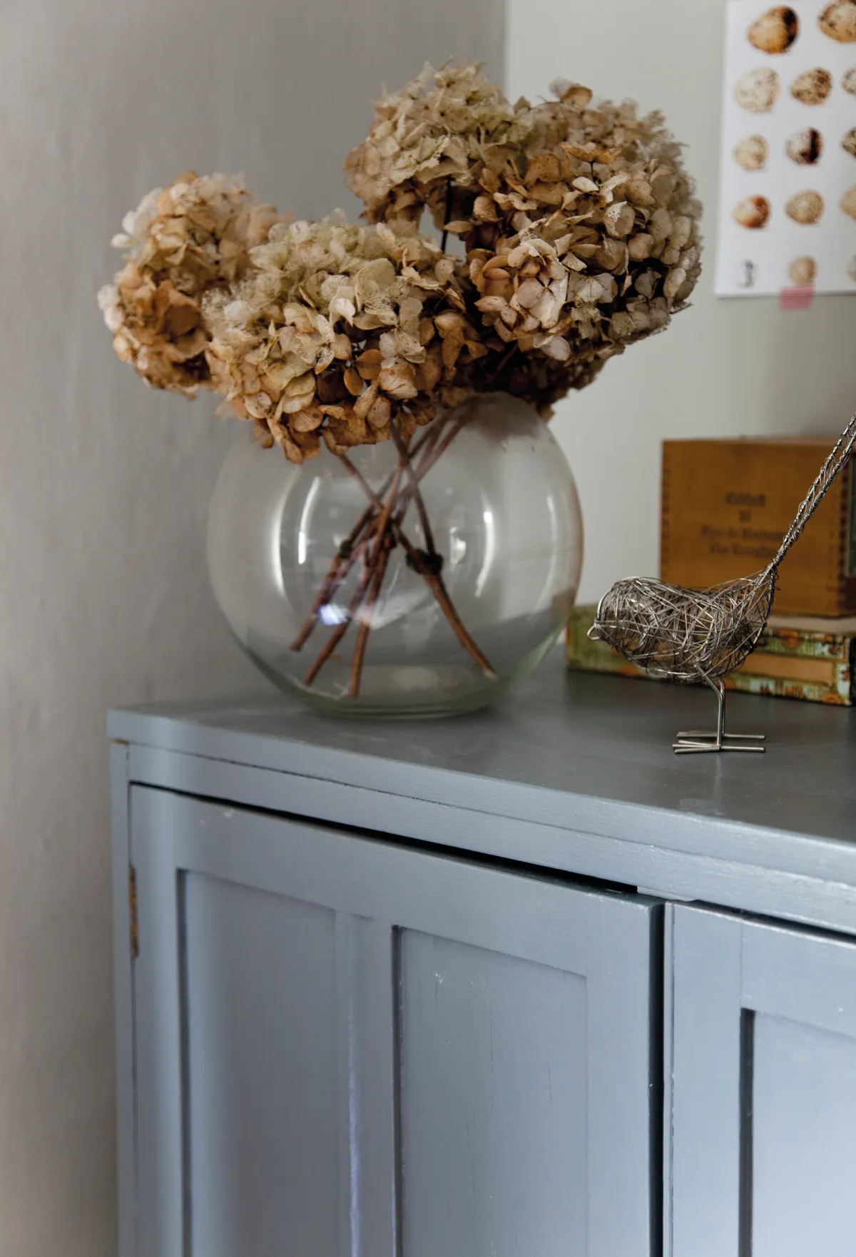 A round glass vase full of dried hydrangeas