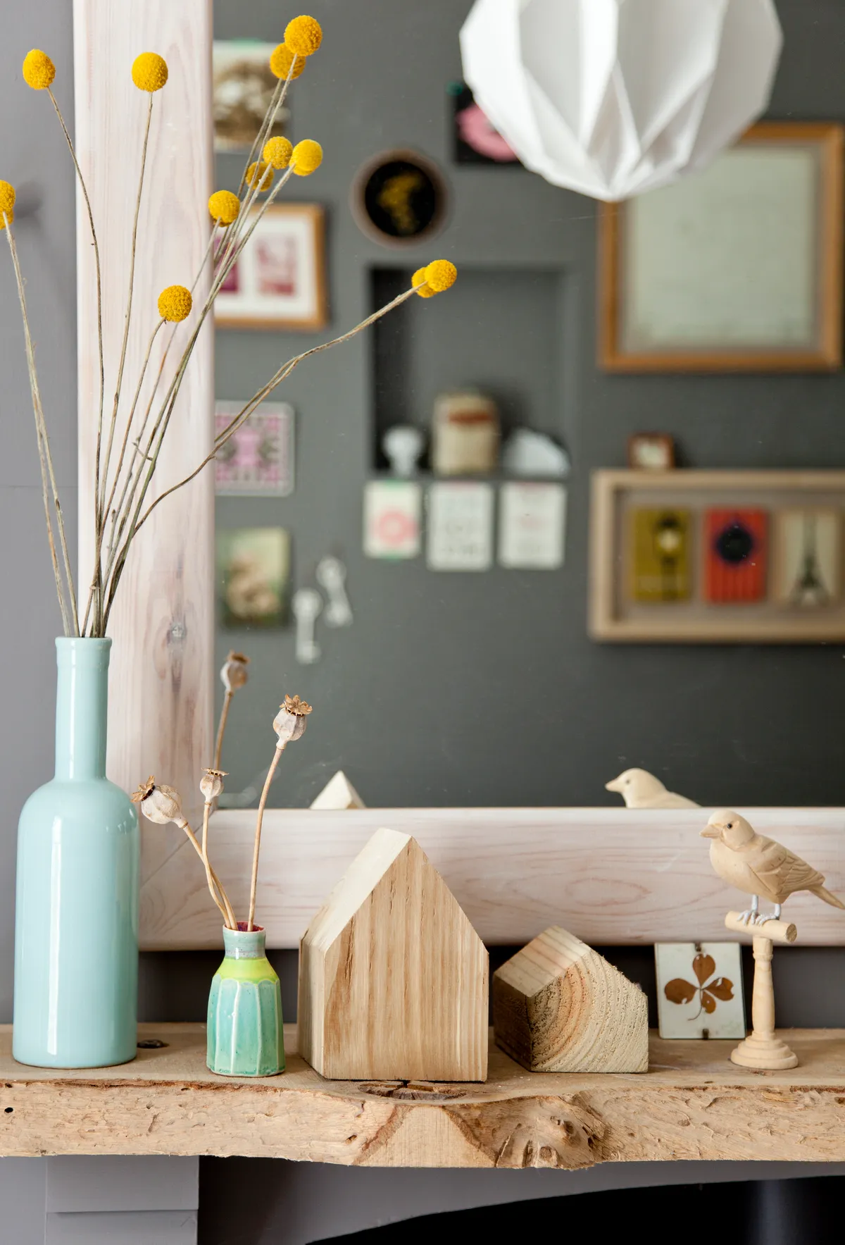 Natural wooden ornaments and a blue vase full of dried yellow flowers