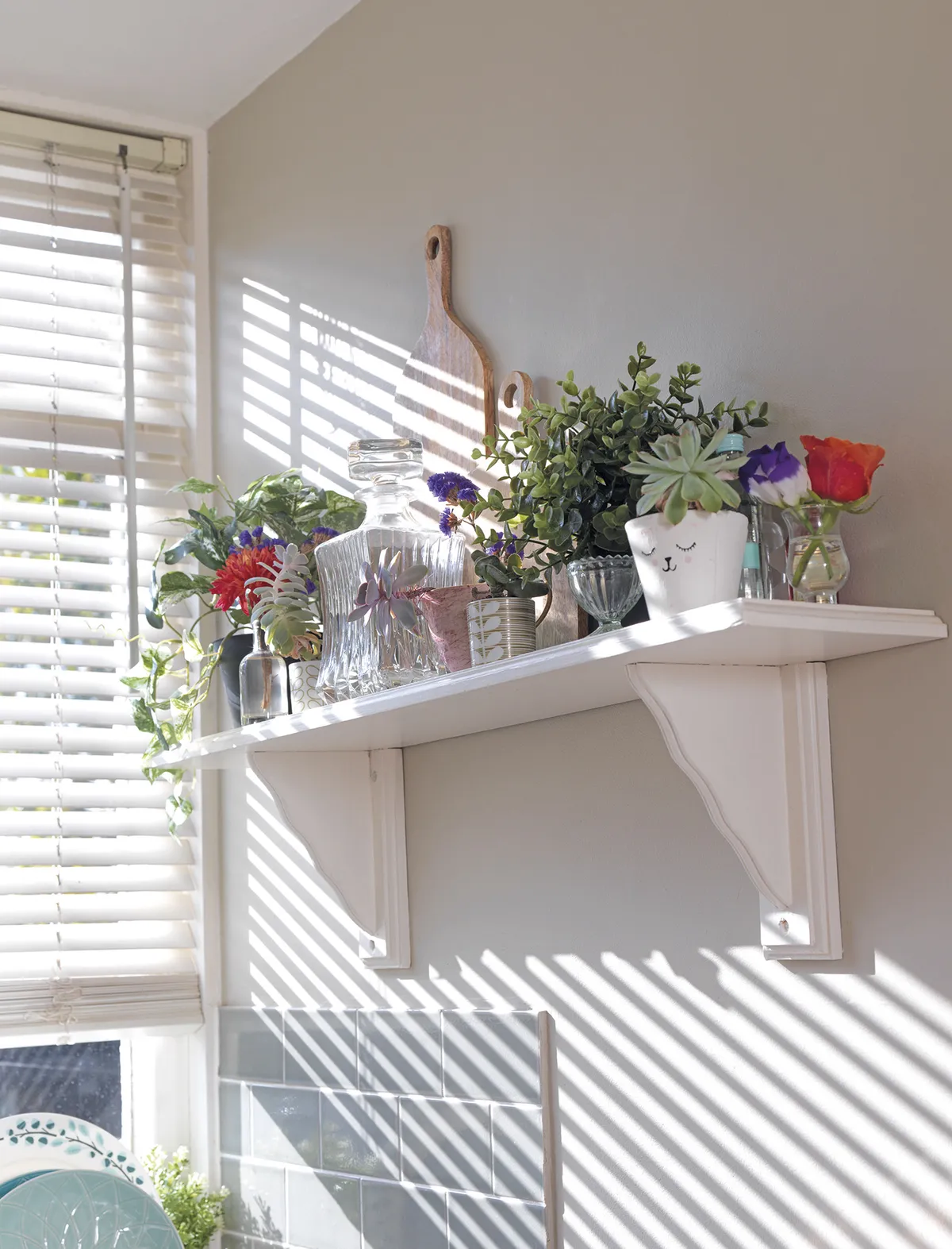 With a combination of chopping boards and glassware, interspersed with succulents, little posies and artificial plants, the shelf above the sink is cleverly arranged, without looking too cluttered