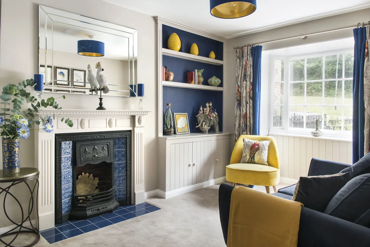 The front room has been turned into a snug with strong blue tones and a bird theme. The fireplace was bought on Facebook Marketplace and upcycled with Minton Hollis Scuba Blue tiles from Topps. ‘The blue velvet and gold lampshade was specially made by Millie & Rose Designs,’ says Charlie