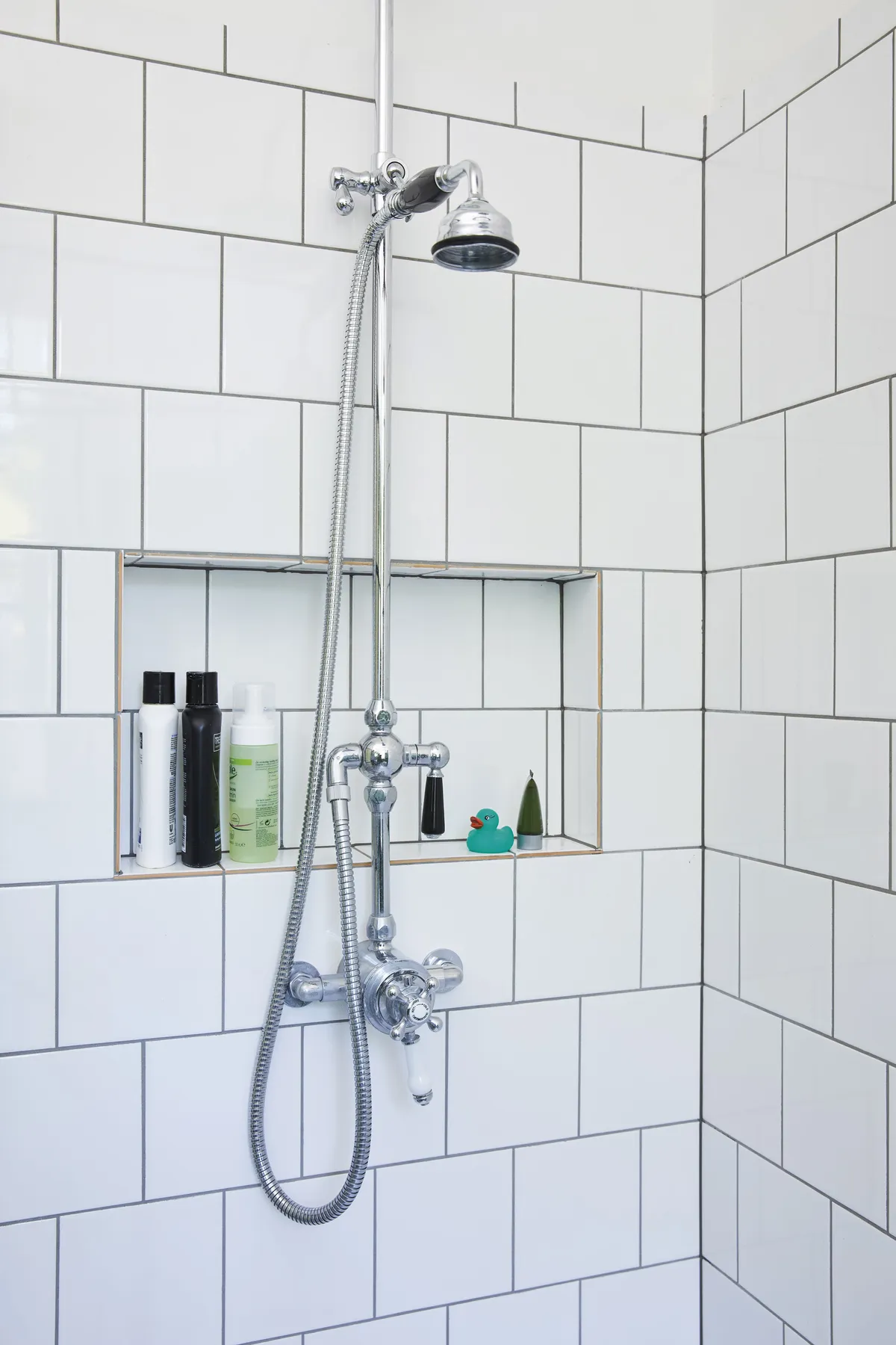 By simply opening up a section of existing stud wall, the couple were able to create a handy recessed storage shelf – perfect for all those showering essentials