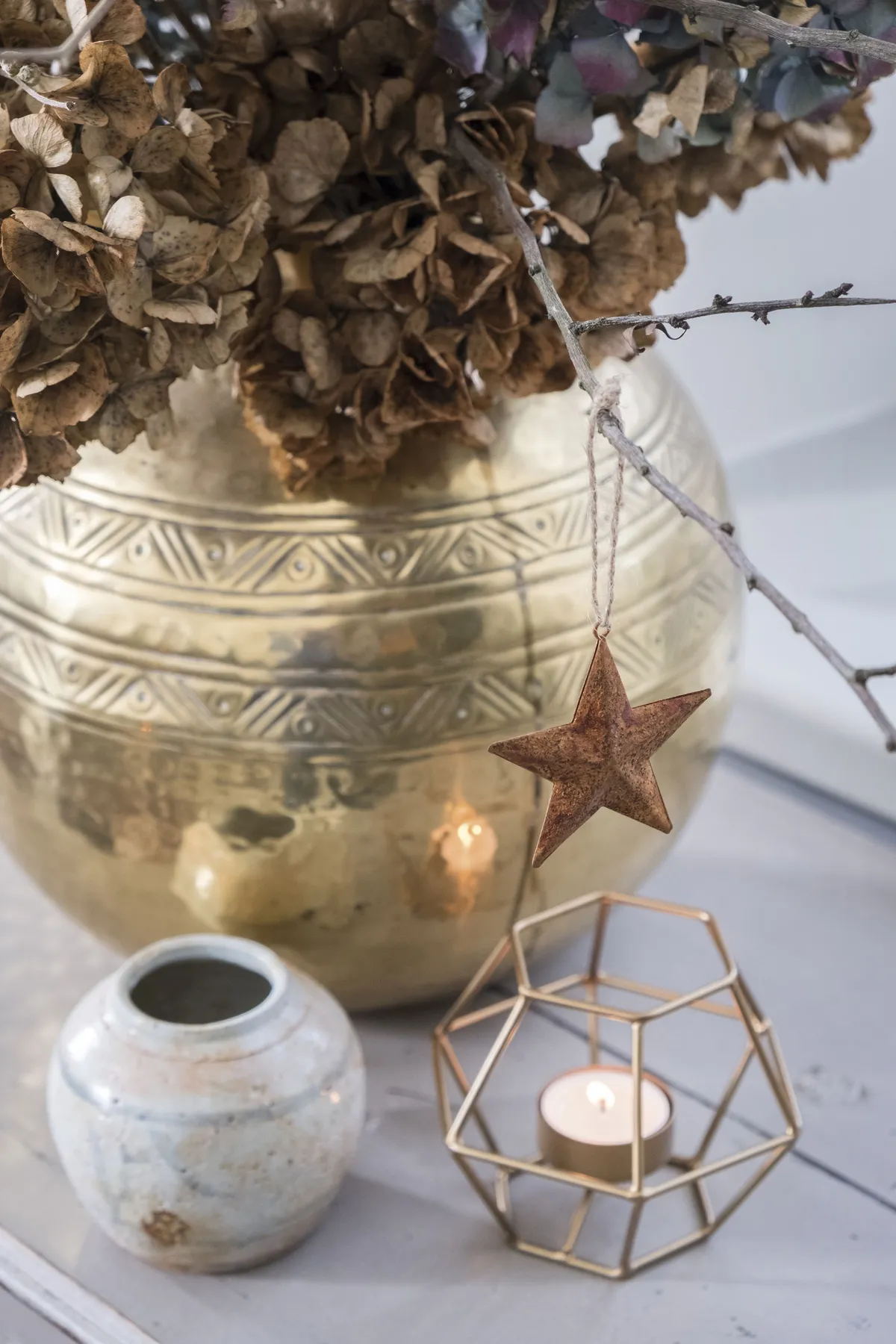 ‘Dried hydrangea heads look festive in a brass vase, and combined with a metallic wire tealight and earthenware pot, they create the rustic feel I love,’ says Kay