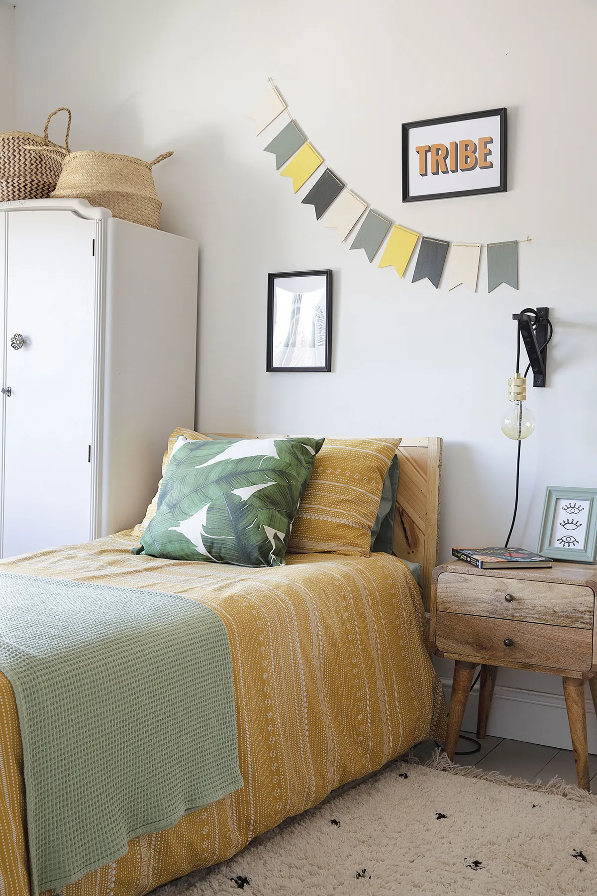 Mustard bedding and a palm leaf cushion from H&M Home complement the jungle wallpaper. Laura upcycled the second-hand wardrobe and made the bunting herself