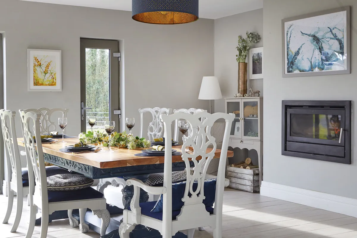 To give her kitchen-diner an opulent feel, Gillian added royal-blue accents to the white and grey scheme, plus co-ordinating artwork and new covers on second-hand chairs