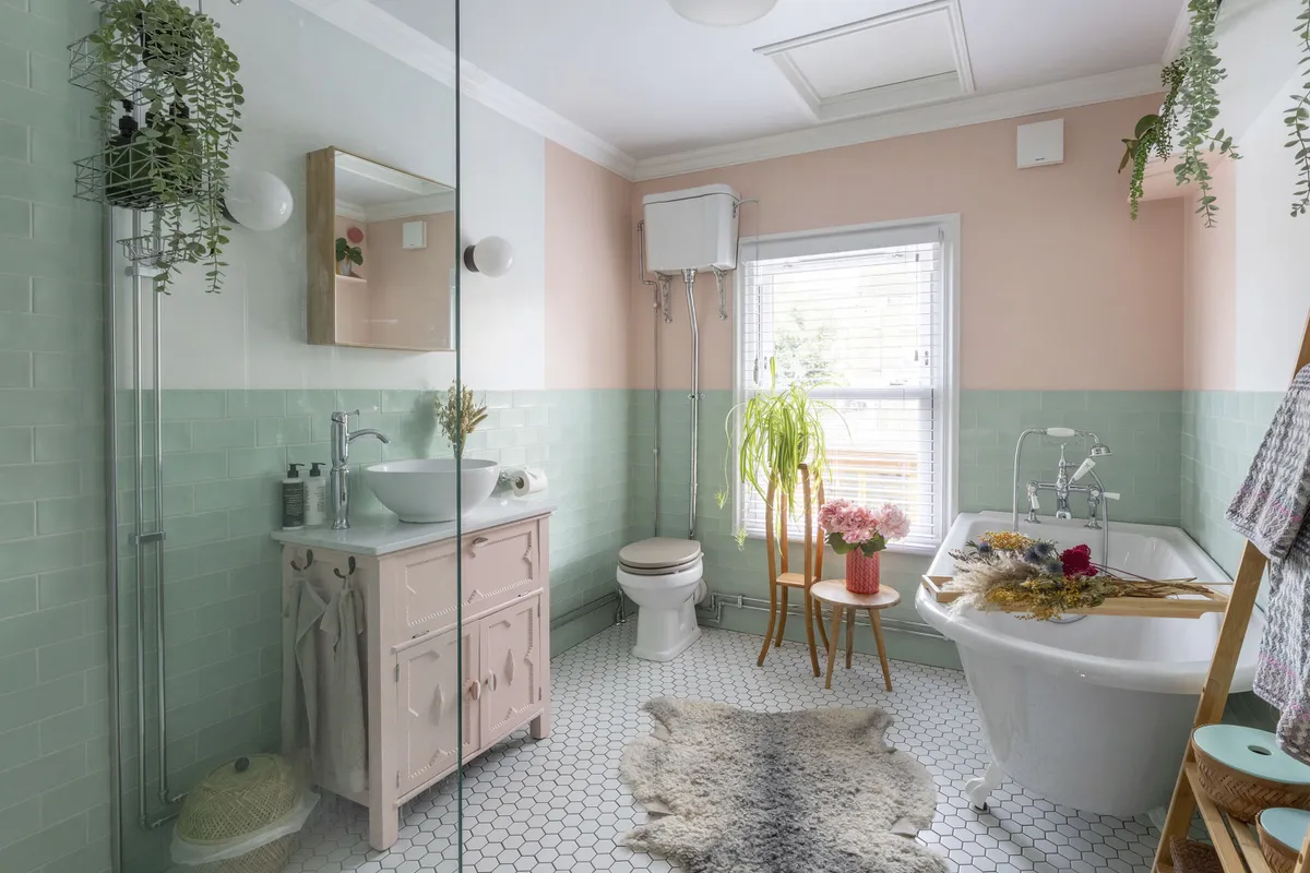 A traditional toilet and bath sit beautifully alongside modern pink and off-white walls, Victoria Plum Annecy Green matt wall tiles and Tiles Direct white and pink Hex floor tiles