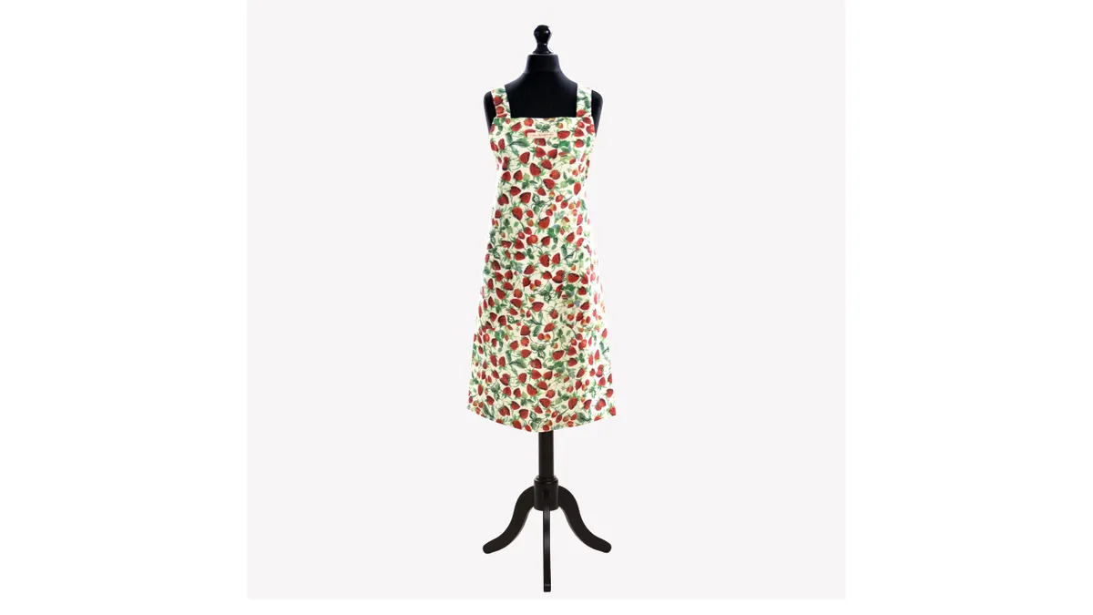 An apron with a strawberry print on a black mannequin.