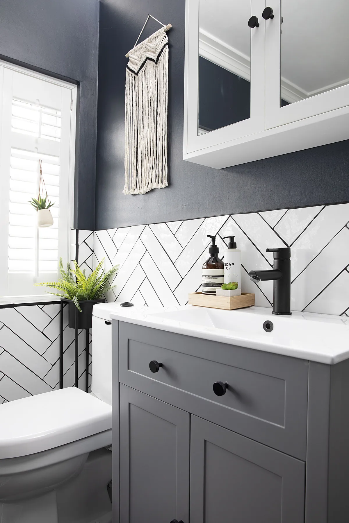 Claire and Craig saved money by keeping the existing toilet, and the vanity unit and wall cabinet from the mini makeover they did when they first moved in. To define the white and grey elements of the scheme, Claire used striking black grout and tile trims