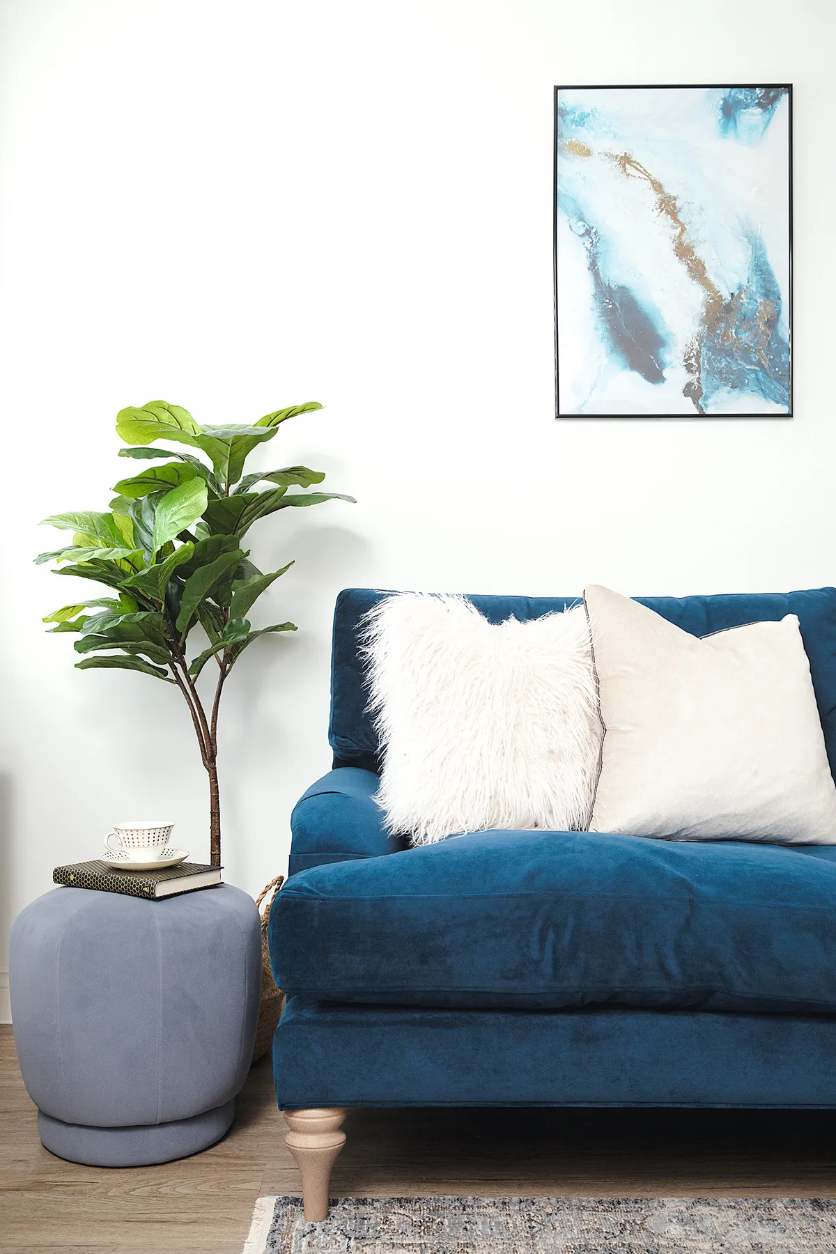 ‘I bought the blue and gold artwork from Desenio to tie in with the navy sofa. The upholstered stool from HomeSense makes a lovely side table’
