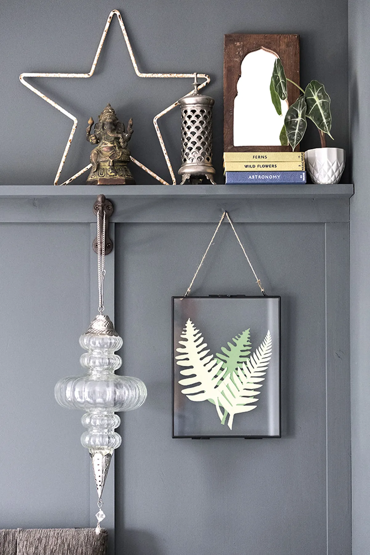 Colin added a ledge shelf for prints and trinkets, and Sarah framed the bed with glass ornaments hung on hooks to add interest. The botanical artwork is Colin’s – he created it from cut-out paper leaves