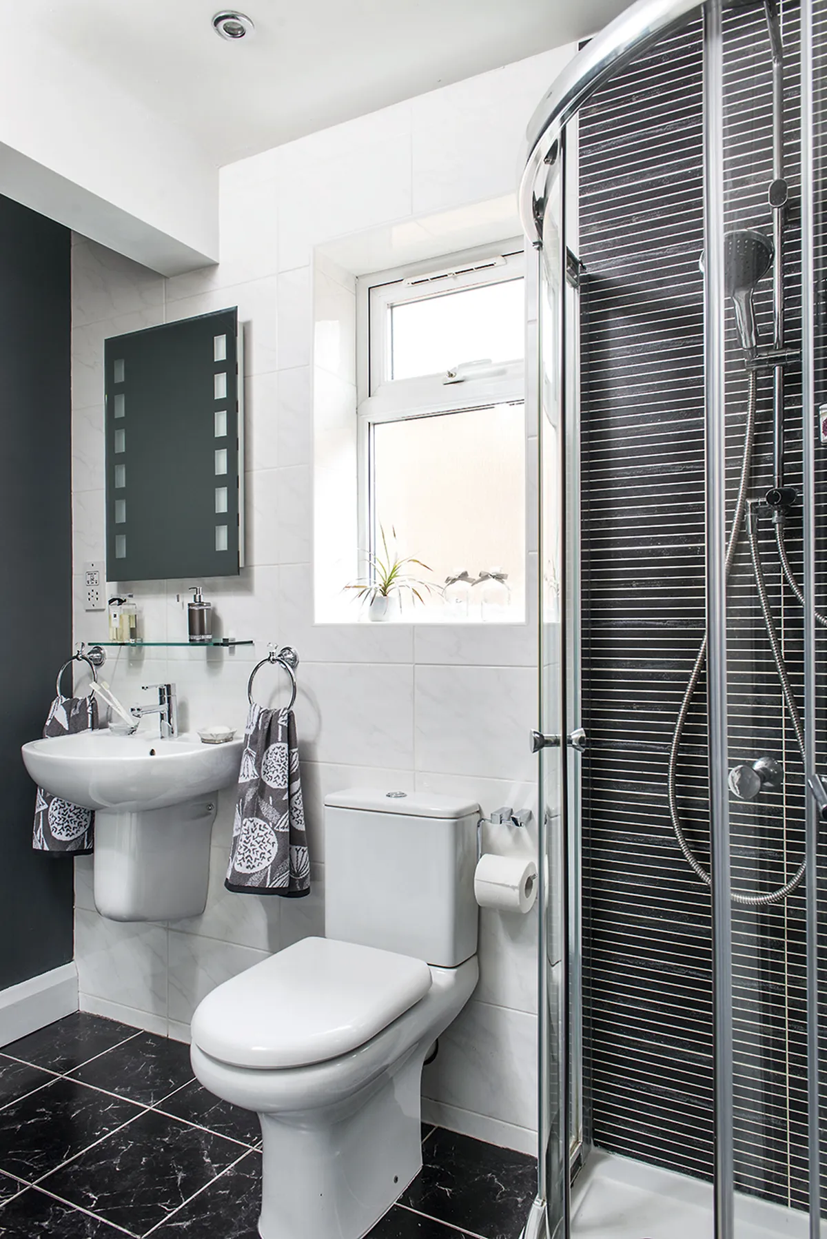 Sarah chose three different tiles from Supatile, going for a monochrome scheme to tie the styles together, complemented by graphic towels from Dunelm. Black marble floor tiles give a luxe spa feel, while narrow tiles in the shower zone the space
