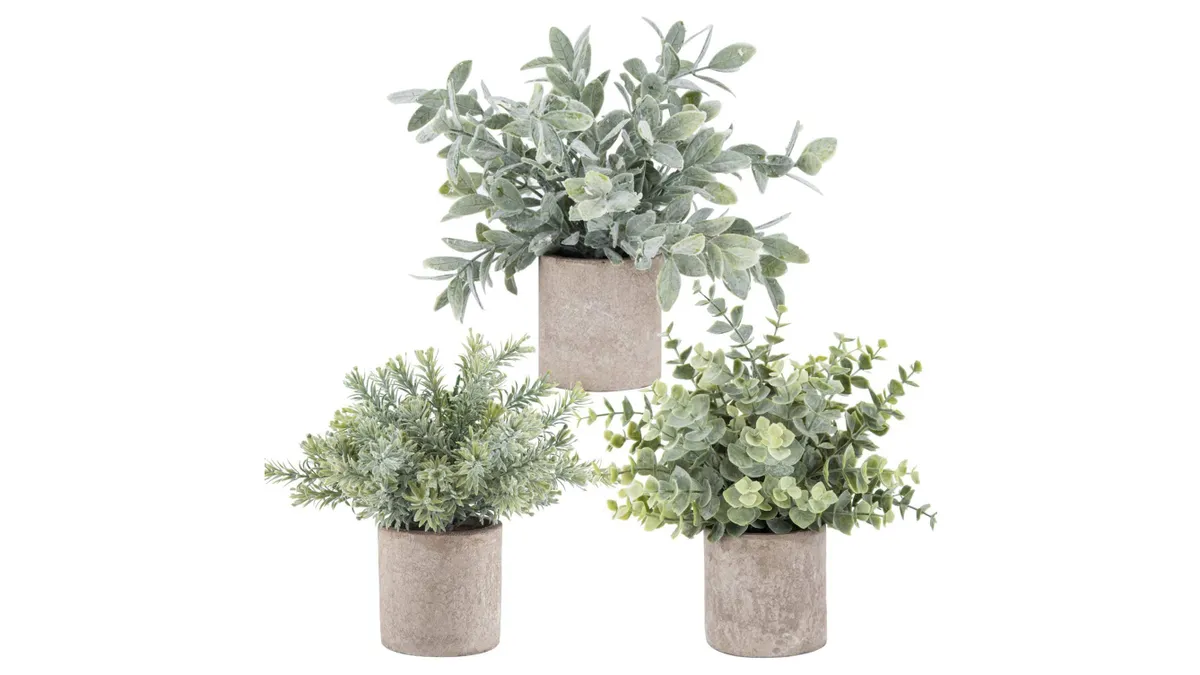 Three potted artificial plants on a white background.