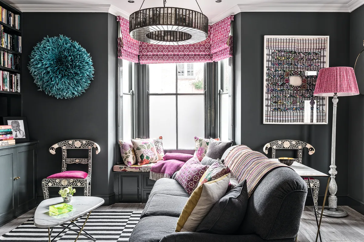 Downton chandelier above grey sofa with Juju tribal hat and framed huipil from Guetemala