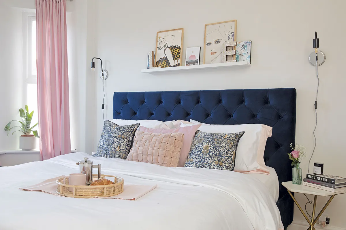 ‘We chose Strong White by Farrow & Ball for the walls with a dark blue bed from MADE.com to contrast. The side table is from Swoon and the wall lights are from Iconic Lights’