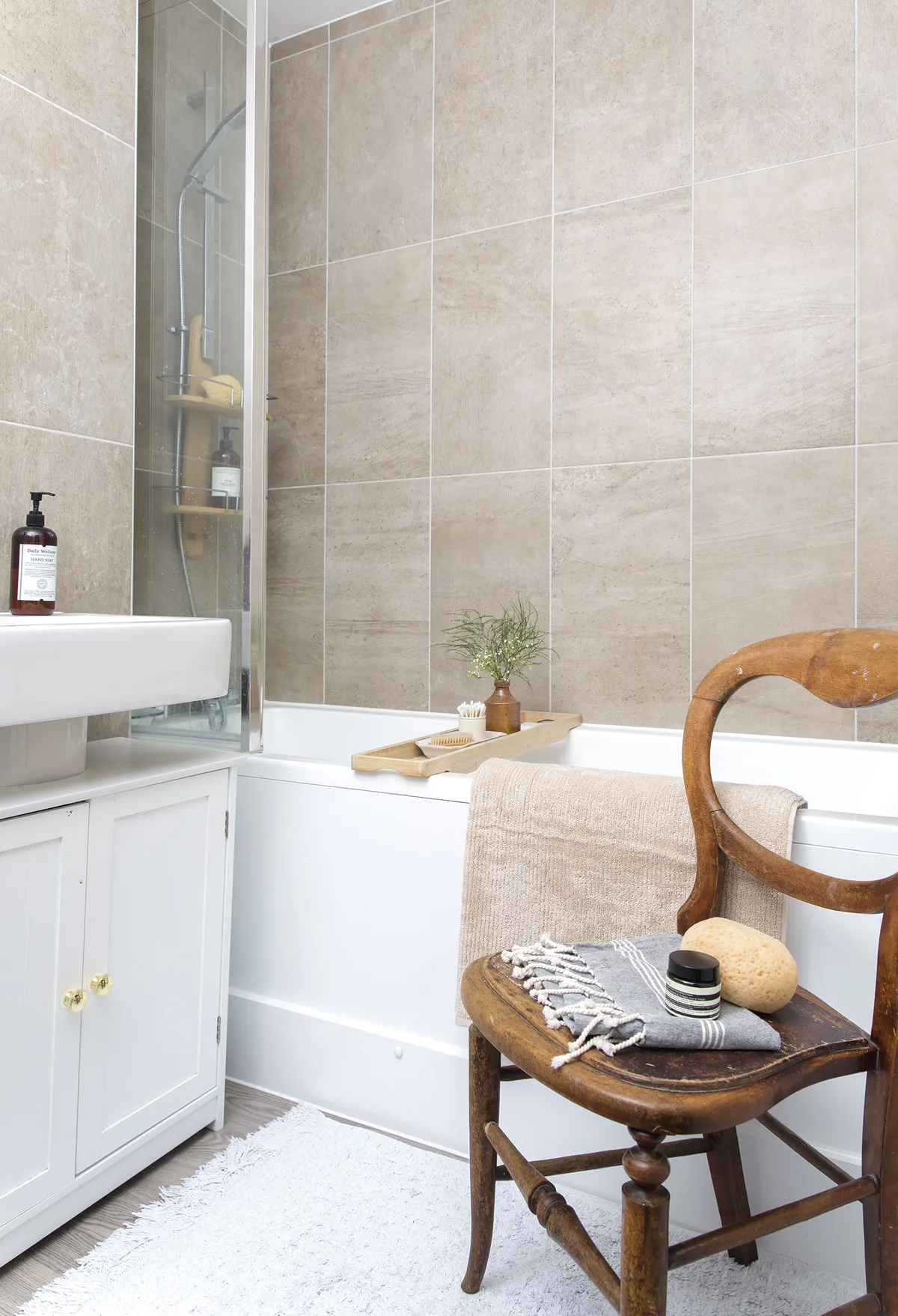 Rectangular-shaped beige tiles line the bathroom walls, with standard white fittings that were all part of the new-build décor. Tilly added the small cabinet from B&M under the sink to store cleaning products