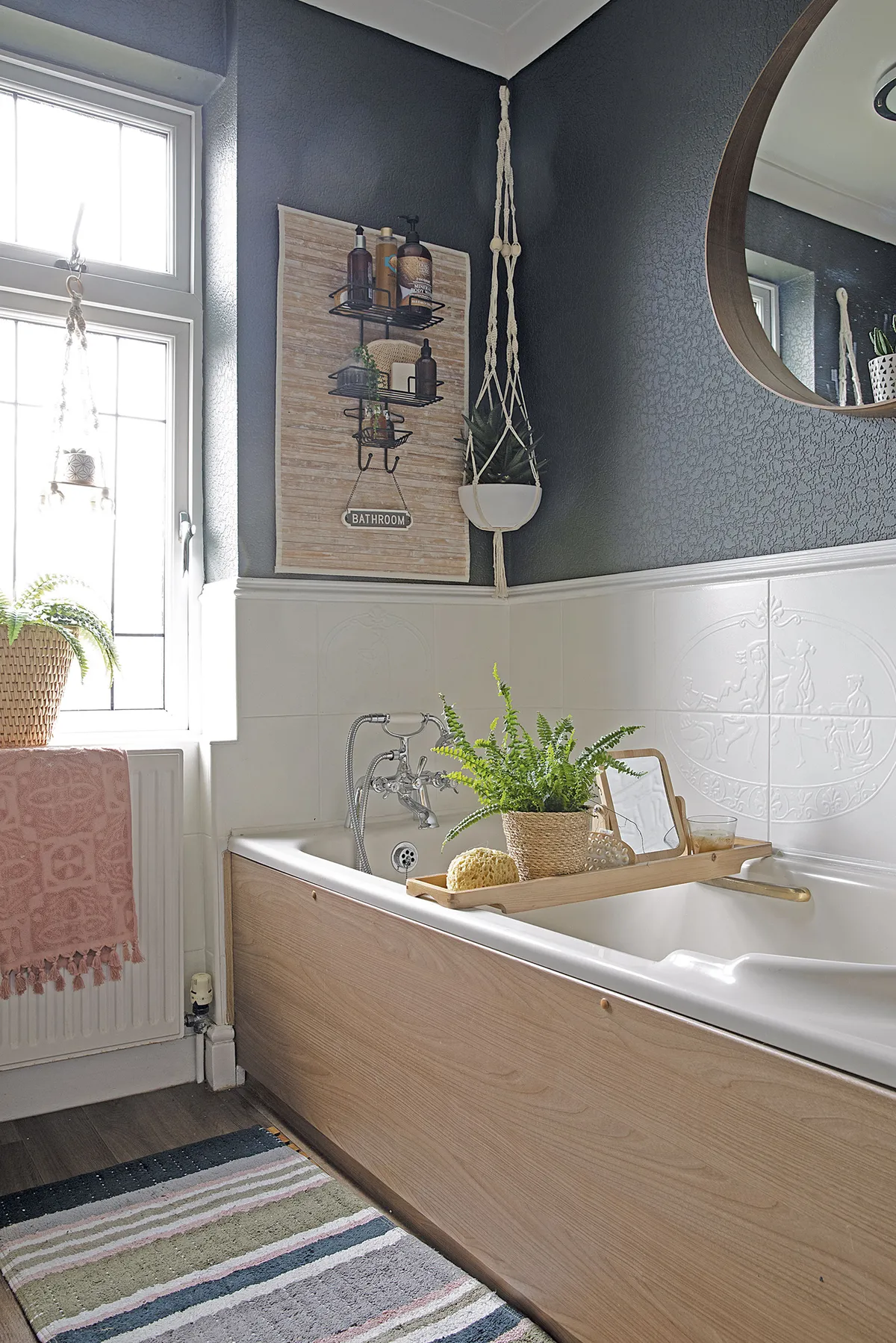 The old bathroom suite has been dressed up with an IKEA mirror, George Home bathmat and bath bridge. ‘To make a feature on the wall I created some storage using a spare bathmat and shower caddy,’ says Leanne