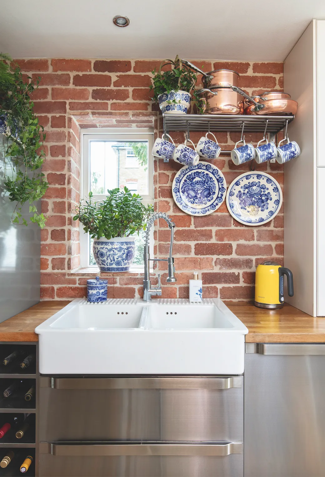 With its bare-brick wall, blue-and-white plates and mugs, sleek stainless-steel units and copper accessories, Anna has gone for a mix of rustic industrial and classic vintage styles in the kitchen