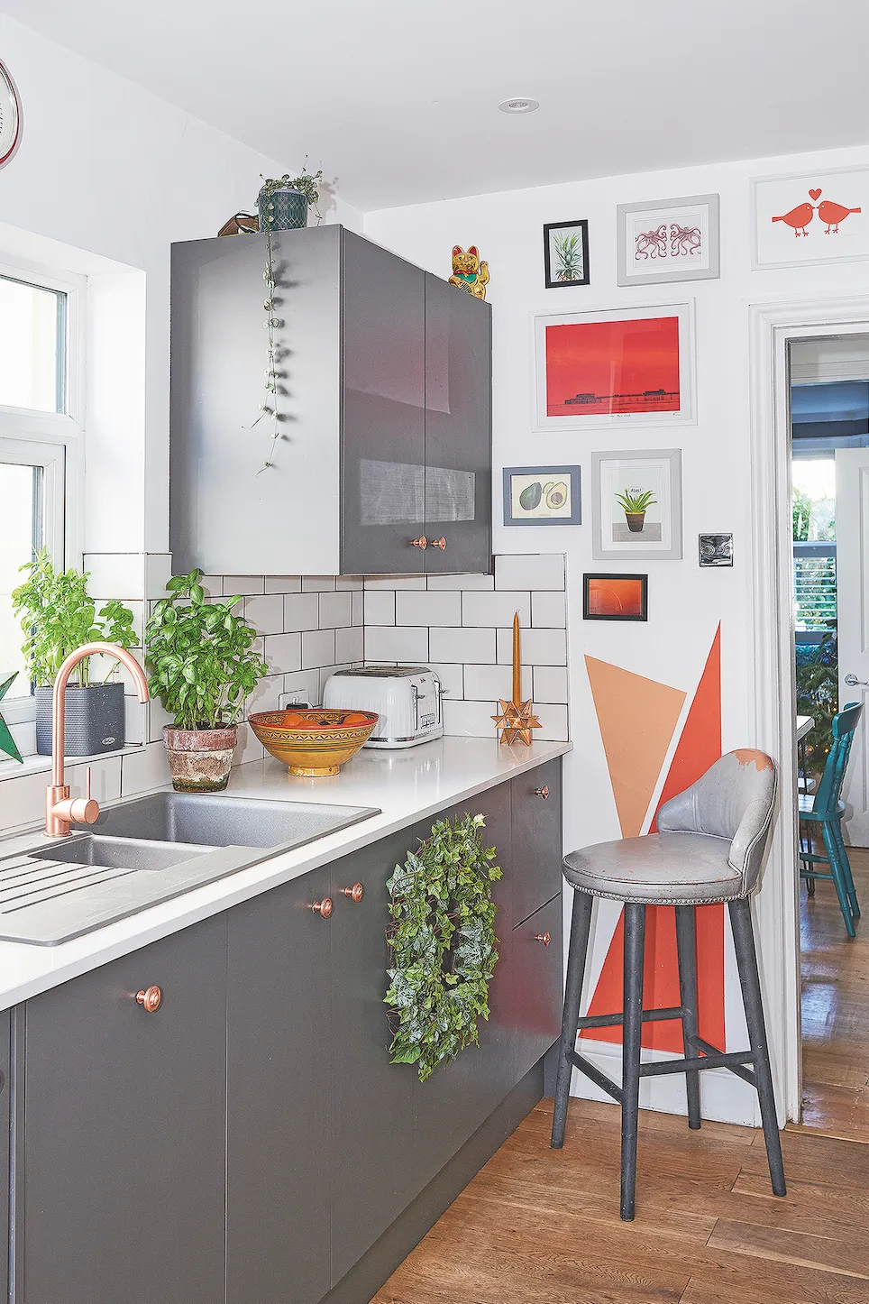 Painted triangles on the opposite wall tie in with Nikki’s mural by the patio door, and she’s matched the fiery orange tones with cabinet knobs and a Howdens’ swan neck tap in copper