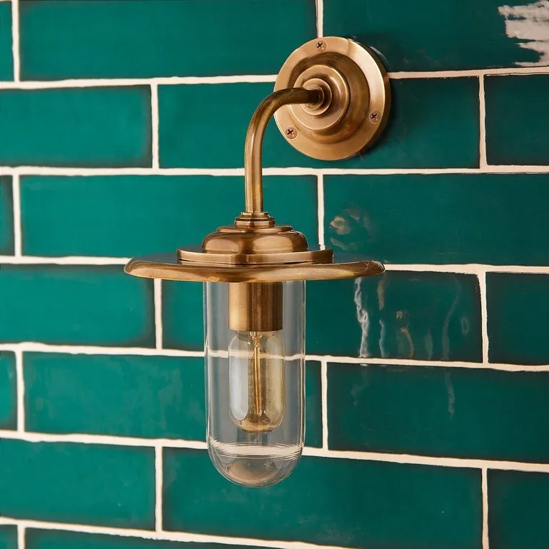 Brass wall light on a green tiled wall