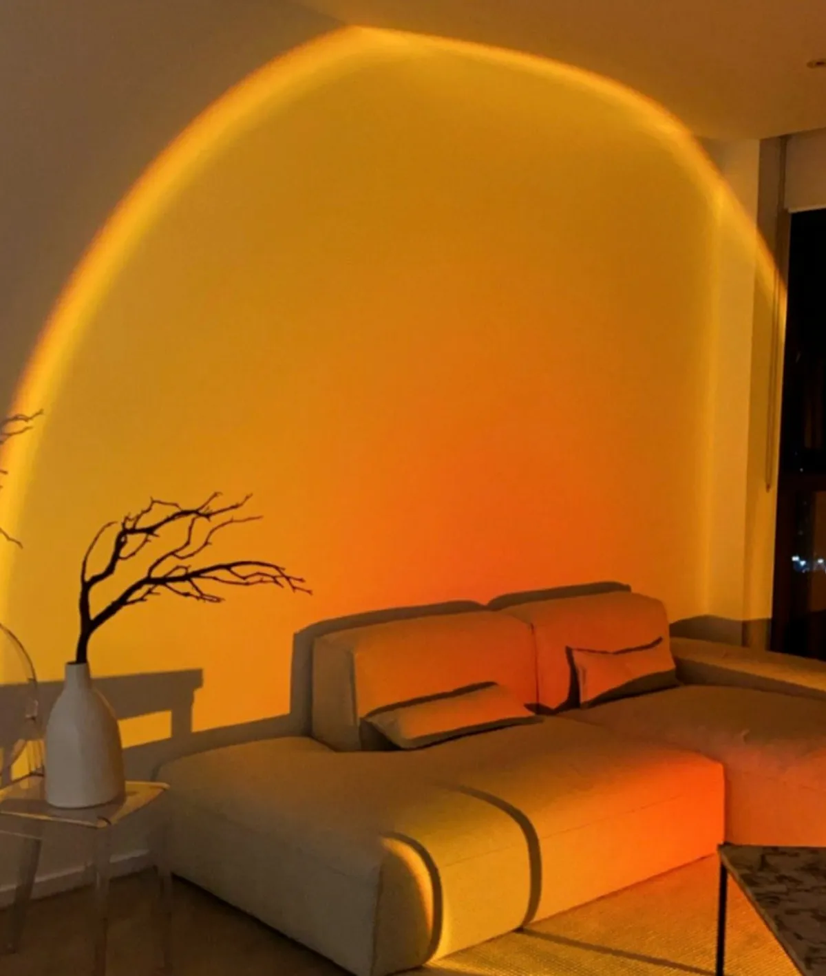 Sunset lamp lighting up a living room with a orange golden glow against a white corner sofa
