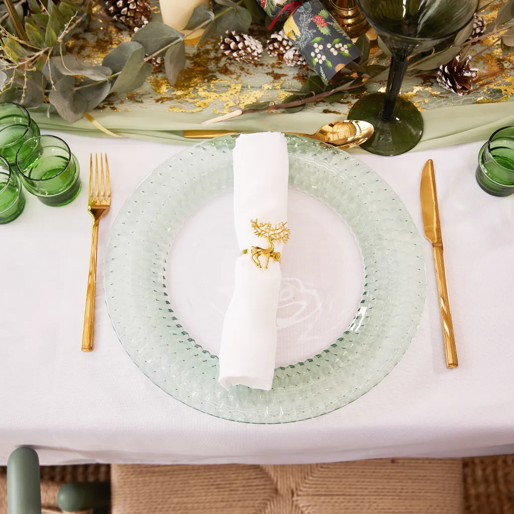 green serving plate, a white napkin and gold cutlery