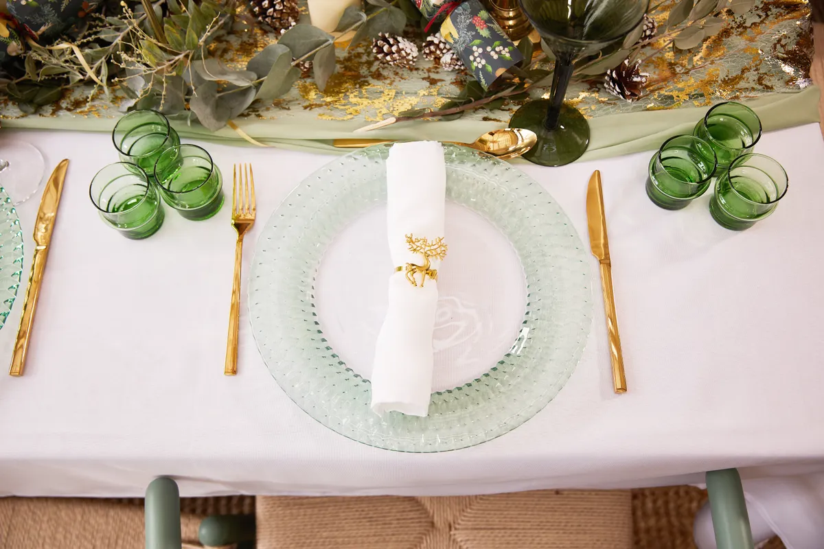green serving plate, a white napkin and gold cutlery