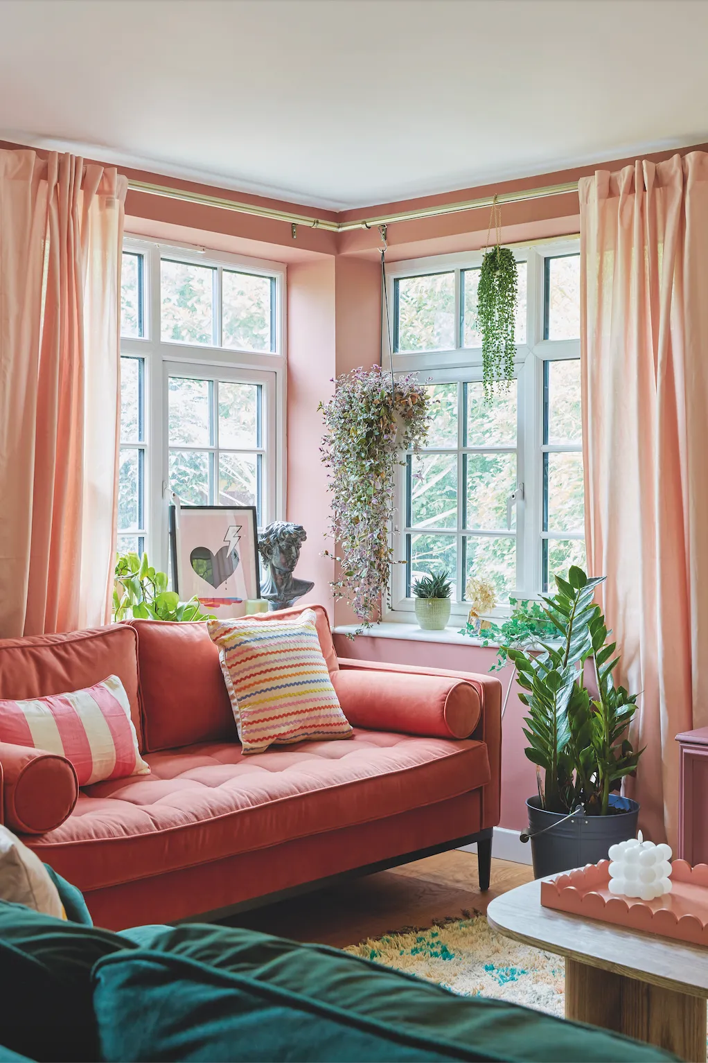 Walls painted in Ashes of Roses by Little Greene are complemented by blush-coloured curtains and a salmon pink sofa from Swyft