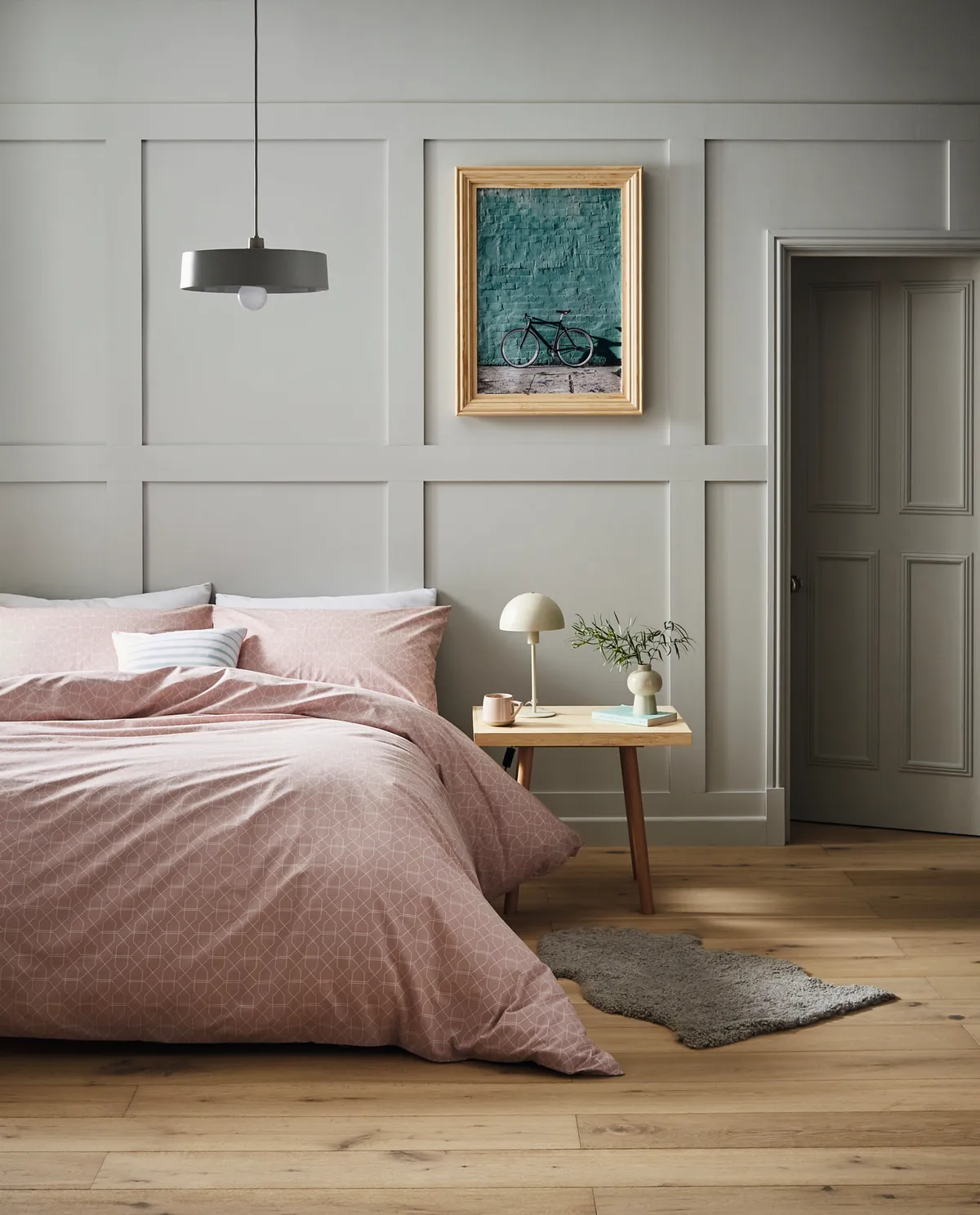 Pink duvet and bed against a panelled wall