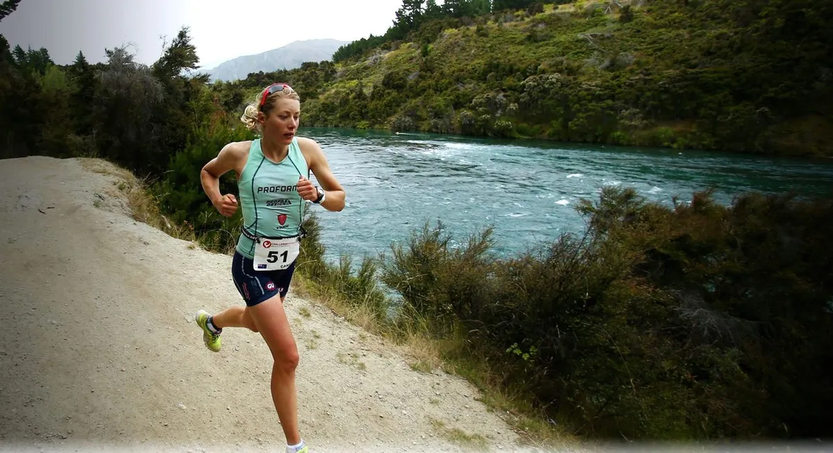 Female triathlete running next to a river